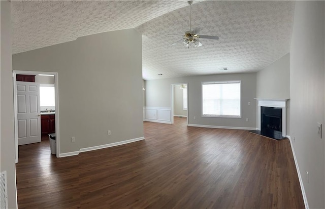 802 Village Pl, Loganville, GA 30052 - unfurnished living room featuring lofted ceiling, a ceiling fan, dark wood finished floors, a fireplace with raised hearth, and baseboards