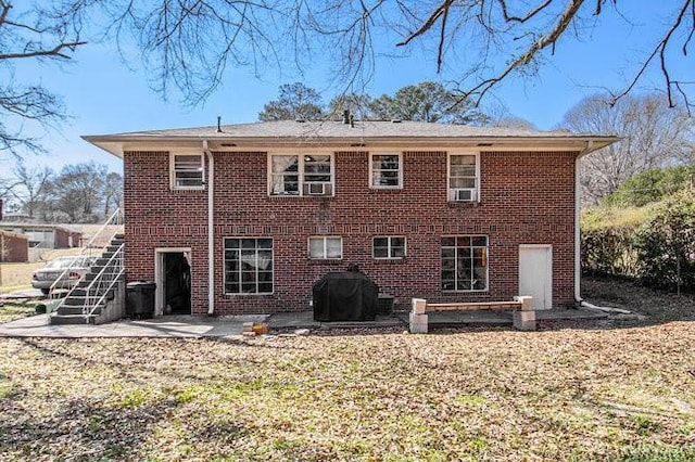 back of house featuring brick siding, a patio, and stairway