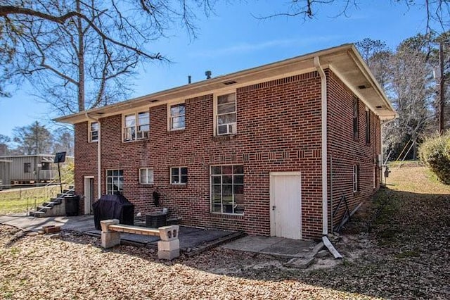 rear view of property with brick siding and a patio