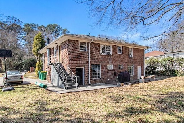 rear view of house featuring a patio area, brick siding, a lawn, and stairway