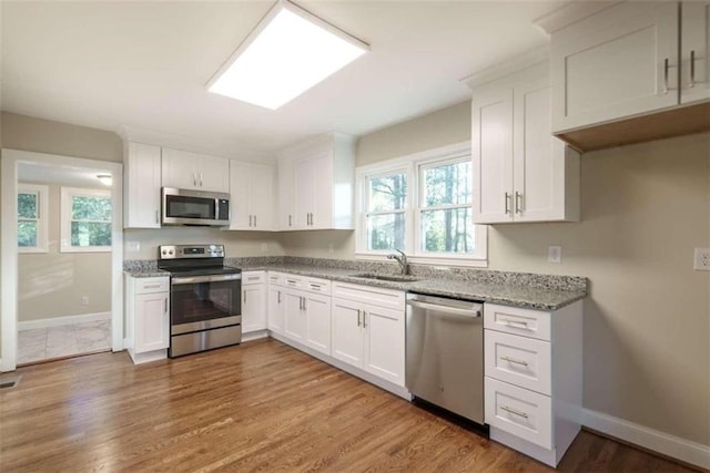 kitchen featuring white cabinets, appliances with stainless steel finishes, sink, and light wood-type flooring