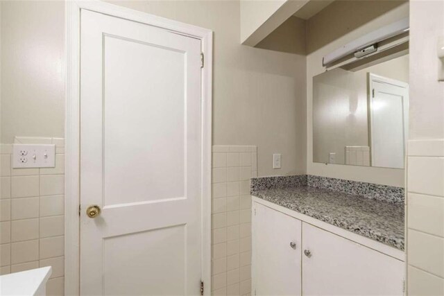 bathroom featuring vanity and tile walls