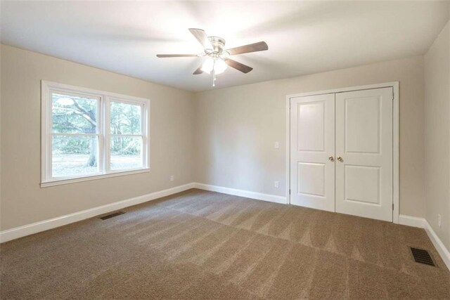 unfurnished bedroom featuring ceiling fan, a closet, and carpet flooring