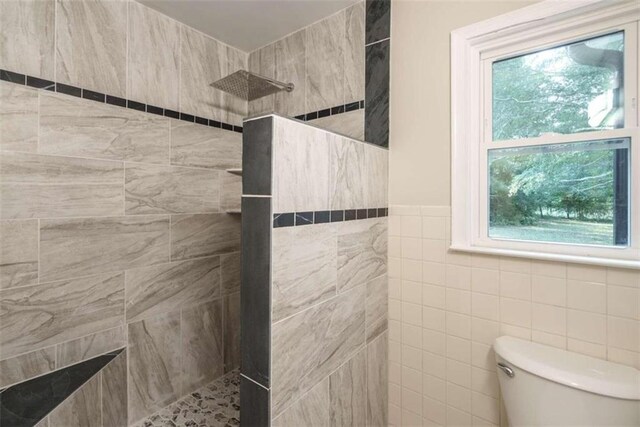 bathroom featuring a wealth of natural light, tiled shower, and toilet