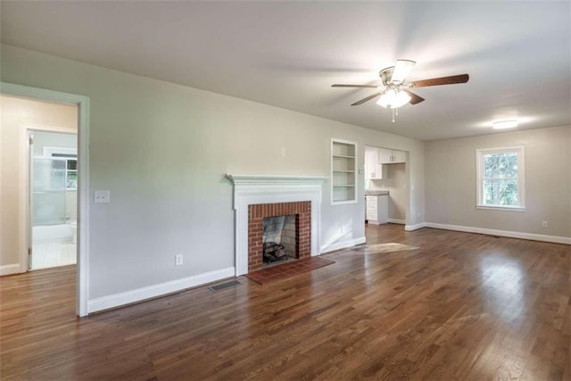 unfurnished living room featuring a fireplace, ceiling fan, built in shelves, and dark hardwood / wood-style flooring