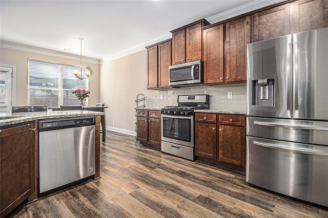 kitchen featuring appliances with stainless steel finishes, decorative light fixtures, crown molding, and light stone counters