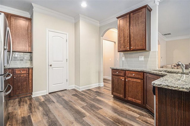 kitchen with dark wood-style flooring, visible vents, a sink, light stone countertops, and stainless steel fridge