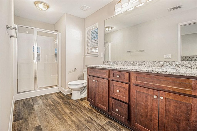 bathroom featuring double vanity, visible vents, toilet, and wood finished floors