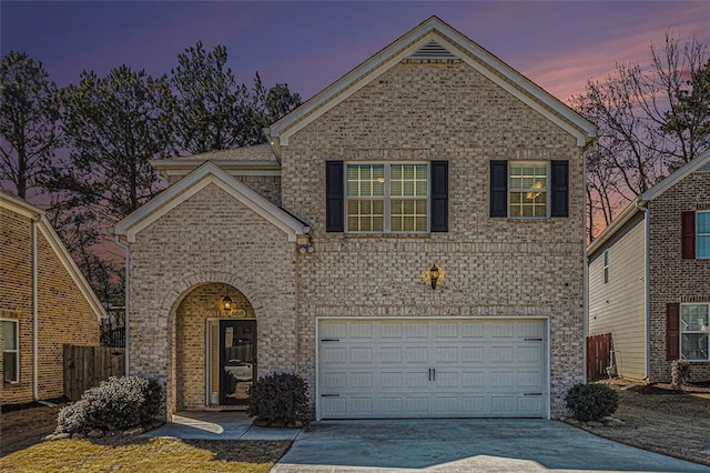 traditional-style home featuring driveway, a garage, and brick siding