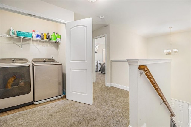 clothes washing area featuring light carpet, laundry area, baseboards, washer and clothes dryer, and a chandelier