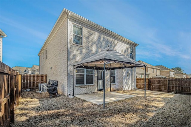 rear view of property with a fenced backyard, a patio, brick siding, and a gazebo