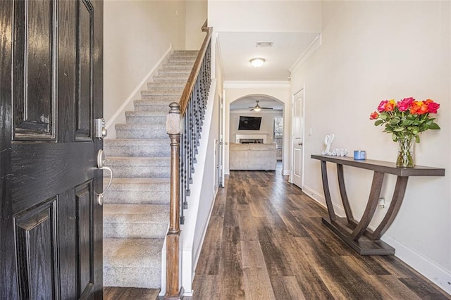 foyer featuring arched walkways, visible vents, stairway, dark wood-type flooring, and baseboards