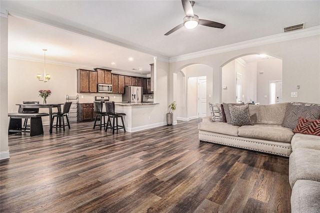 living area featuring arched walkways, dark wood-style floors, visible vents, and crown molding