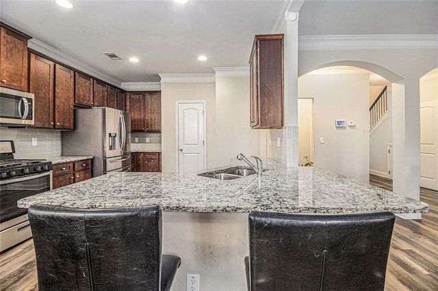 kitchen featuring visible vents, light stone countertops, stainless steel appliances, light wood-type flooring, and a sink