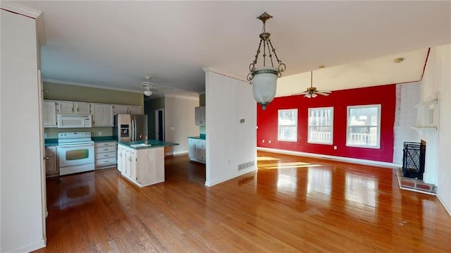 kitchen with ceiling fan, white appliances, wood-type flooring, and a center island