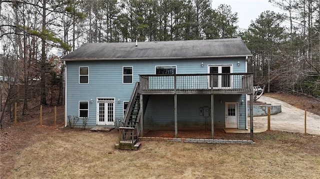 rear view of house featuring a wooden deck, a yard, and french doors