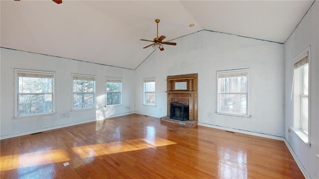 unfurnished living room with a brick fireplace, a wealth of natural light, and ceiling fan