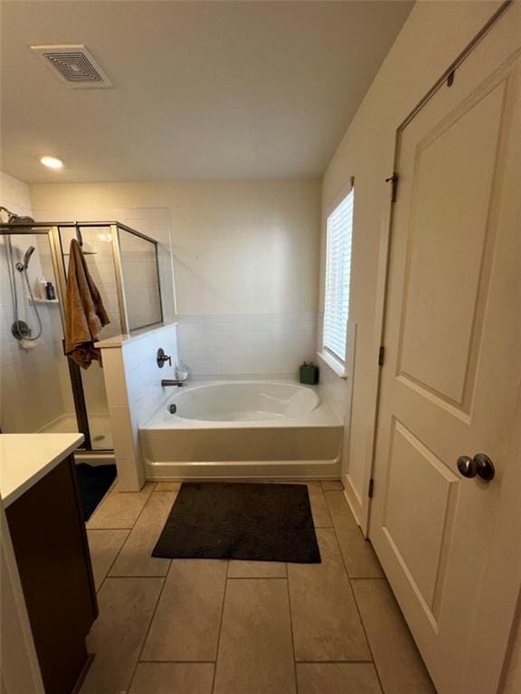 bathroom featuring visible vents, a shower stall, tile patterned flooring, a garden tub, and vanity