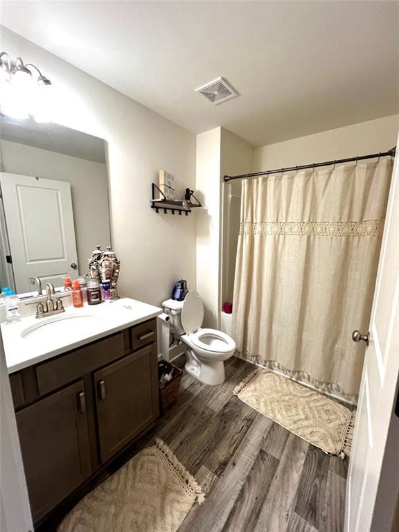bathroom with a shower with curtain, toilet, visible vents, vanity, and wood finished floors
