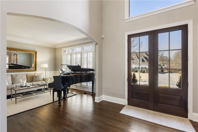 foyer with arched walkways, french doors, plenty of natural light, and wood finished floors