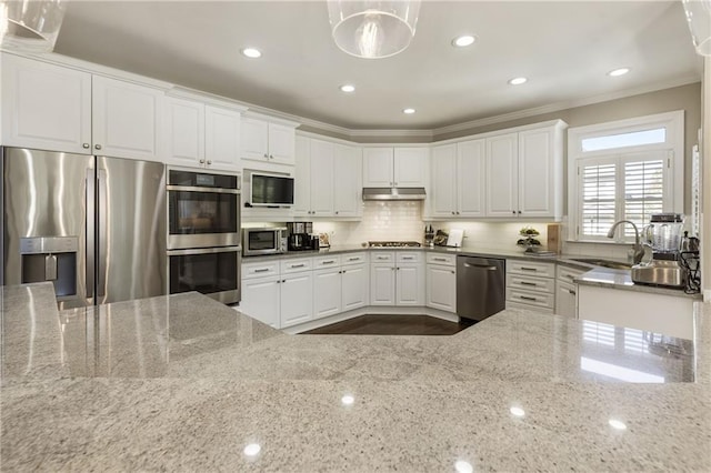 kitchen with appliances with stainless steel finishes, ornamental molding, light stone countertops, under cabinet range hood, and a sink