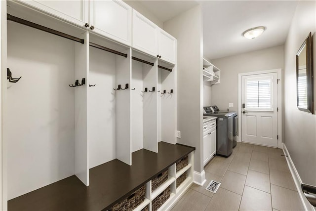 mudroom featuring separate washer and dryer, light tile patterned flooring, visible vents, and baseboards