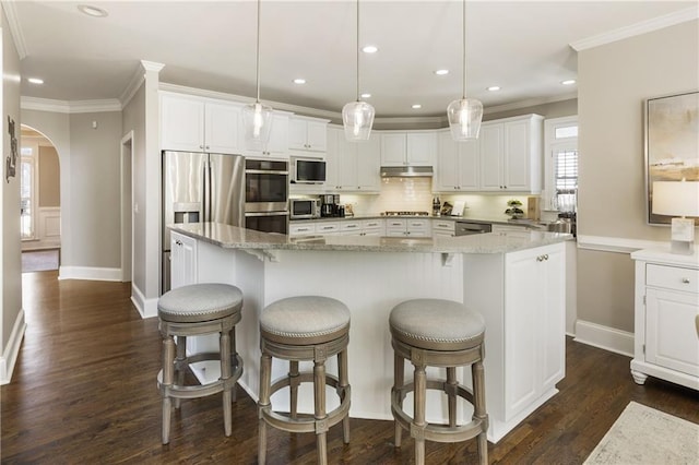 kitchen featuring arched walkways, crown molding, stainless steel appliances, tasteful backsplash, and white cabinetry