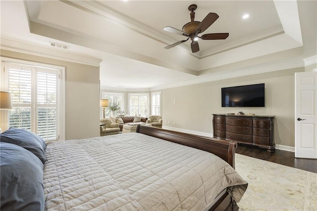 bedroom with ornamental molding, a raised ceiling, and dark wood finished floors