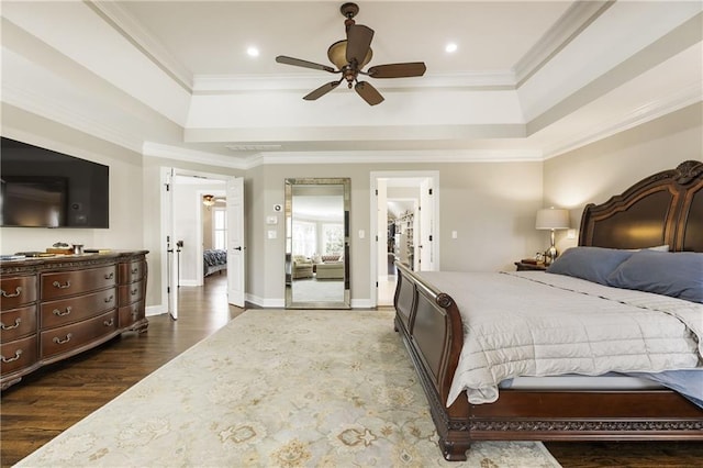 bedroom with a tray ceiling, wood finished floors, and ornamental molding