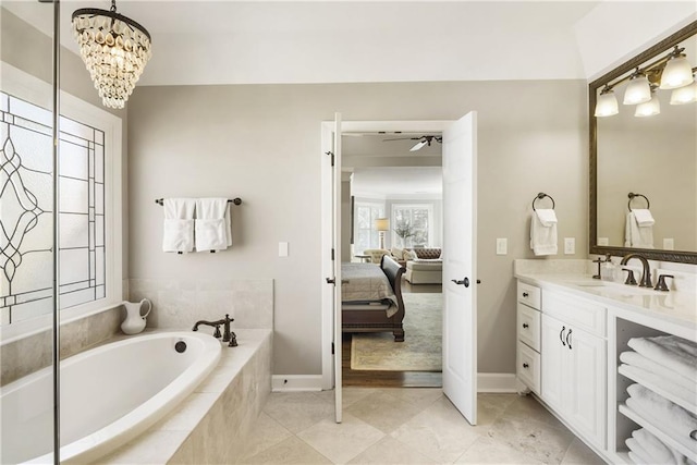 ensuite bathroom featuring ceiling fan with notable chandelier, ensuite bathroom, a bath, and vanity