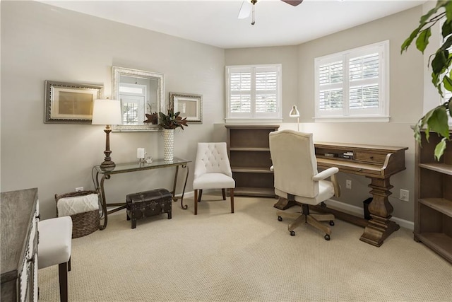 carpeted office space with ceiling fan and baseboards