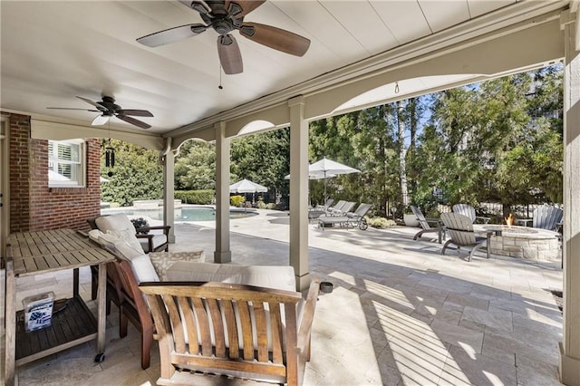 view of patio / terrace with an outdoor fire pit, a ceiling fan, and an outdoor pool