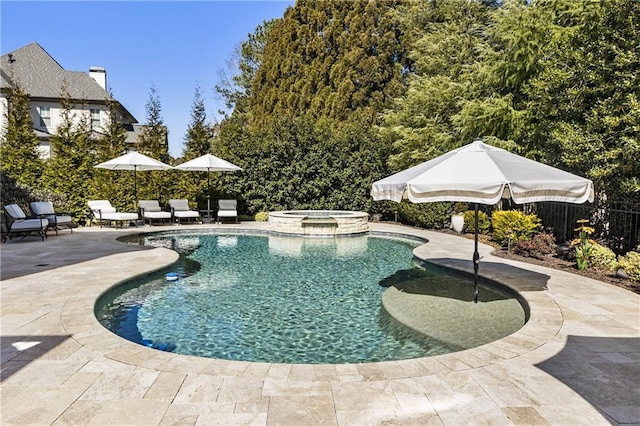 view of pool with a pool with connected hot tub, fence, and a patio