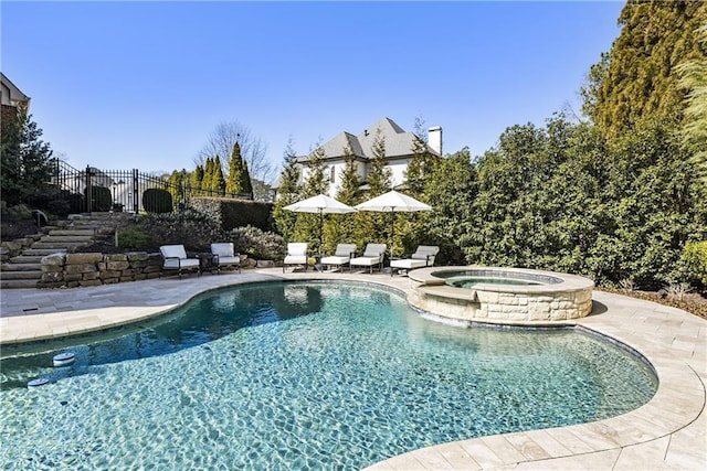 view of swimming pool featuring a pool with connected hot tub, stairs, fence, and a patio