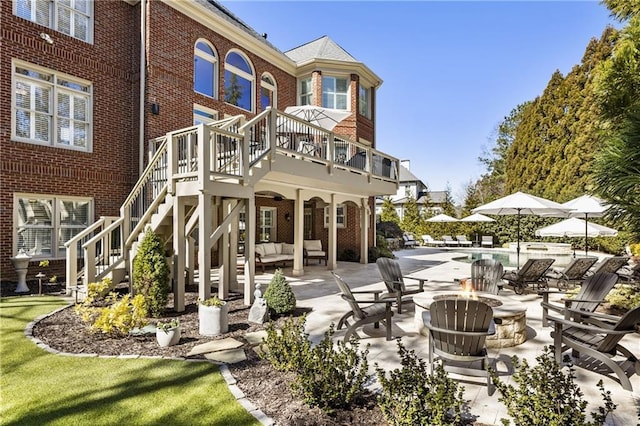 back of property featuring a patio, brick siding, stairway, and an outdoor living space with a fire pit