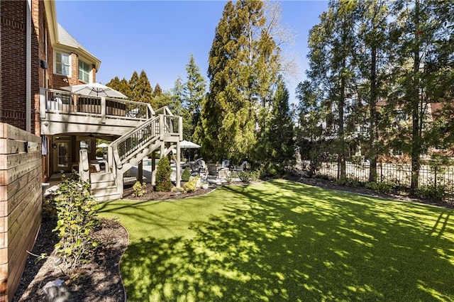 view of yard with fence, a deck, and stairs