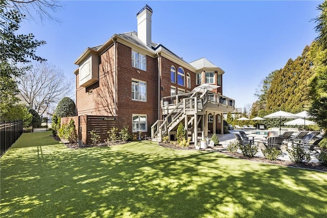 back of property featuring a patio, a chimney, stairs, fence, and brick siding