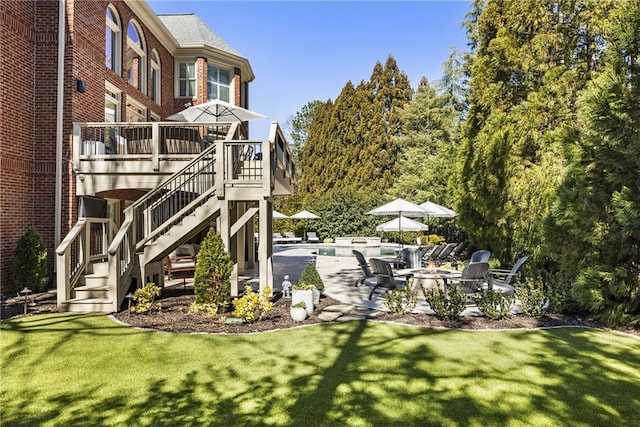 view of yard featuring stairway, a patio area, a deck, an outdoor pool, and a fire pit