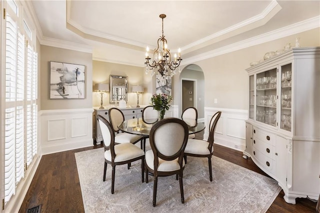 dining room with dark wood-style floors, wainscoting, arched walkways, and an inviting chandelier