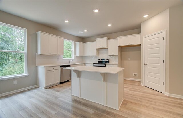 kitchen with appliances with stainless steel finishes, a kitchen island, and a wealth of natural light