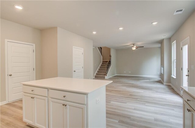 kitchen with ceiling fan, light hardwood / wood-style floors, white cabinetry, and a kitchen island