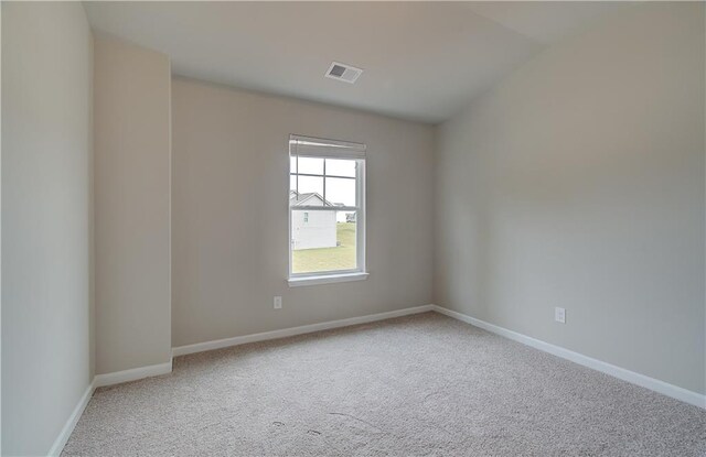 carpeted spare room with vaulted ceiling