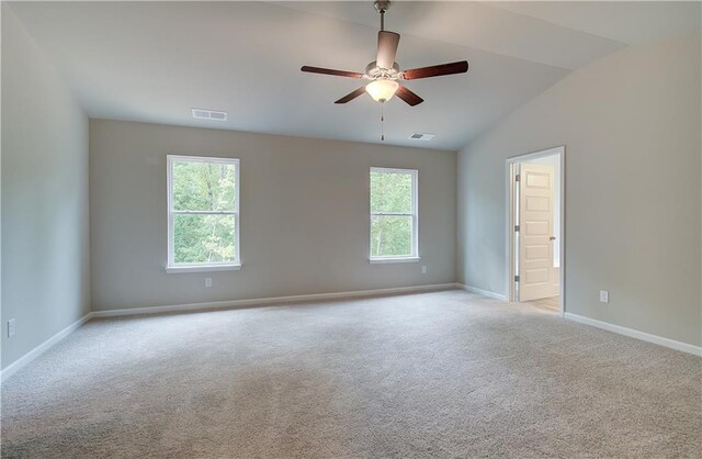 carpeted empty room featuring ceiling fan, a wealth of natural light, and vaulted ceiling