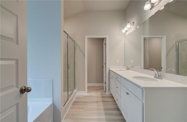 bathroom featuring vanity, shower with separate bathtub, lofted ceiling, and hardwood / wood-style floors