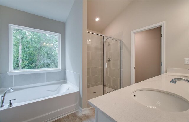 bathroom with lofted ceiling, hardwood / wood-style floors, separate shower and tub, and vanity