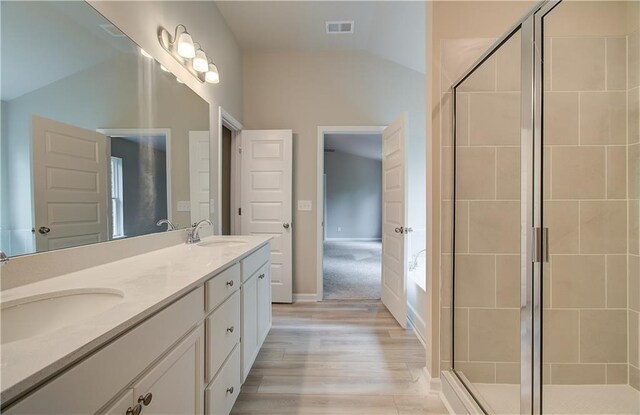 bathroom with walk in shower, vanity, vaulted ceiling, and hardwood / wood-style flooring