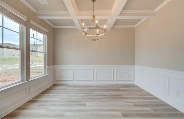 empty room featuring ornamental molding, beam ceiling, coffered ceiling, an inviting chandelier, and light hardwood / wood-style floors