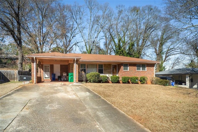 single story home featuring brick siding, fence, driveway, a carport, and a front yard