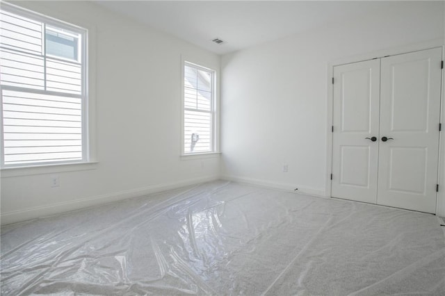 unfurnished bedroom with multiple windows, light carpet, and a closet