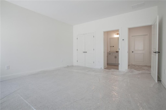 unfurnished bedroom featuring connected bathroom and light carpet